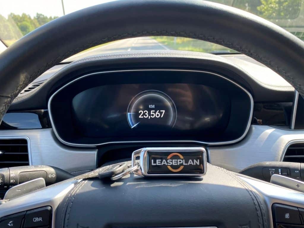 Moderne auto dashboard met digitale kilometerteller en leasesleutels op lederen stuurwiel in daglicht